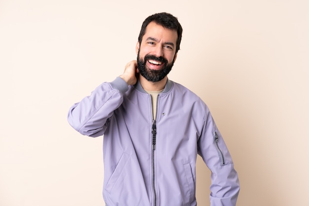 Caucasian man with beard wearing a jacket over isolated background laughing