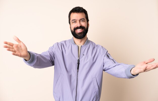 Caucasian man with beard wearing a jacket over isolated background presenting and inviting to come with hand