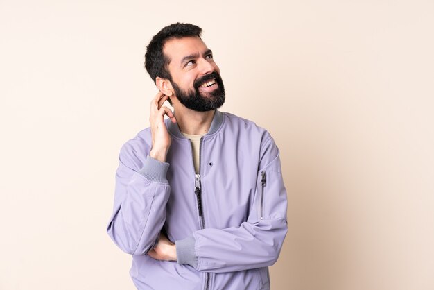 Caucasian man with beard wearing a jacket over isolated background thinking an idea