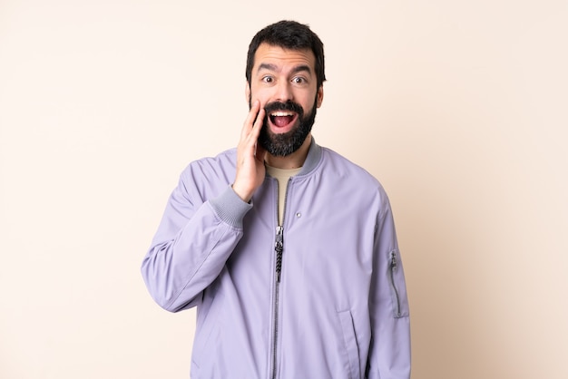 Caucasian man with beard wearing a jacket over isolated background with surprise and shocked facial expression