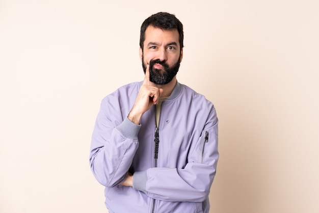 Caucasian man with beard wearing a jacket over isolated and thinking