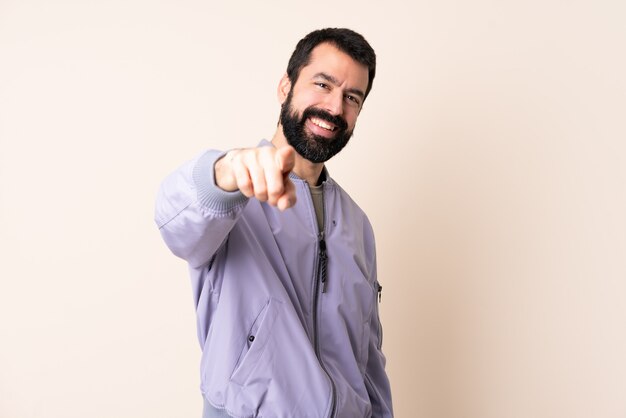 Caucasian man with beard wearing a jacket pointing front with happy expression