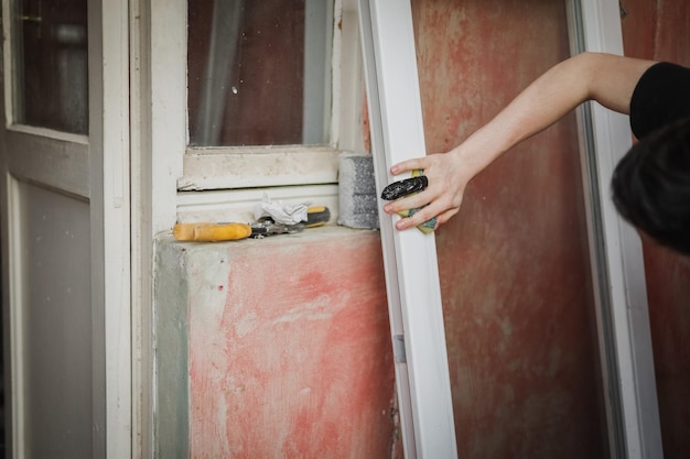 A caucasian man with a black tape tied to his injured finger washes the window frame