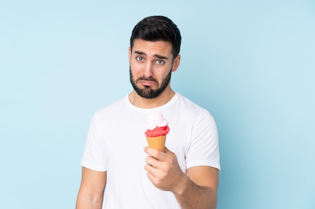 Caucasian man with a cornet ice cream on blue wall