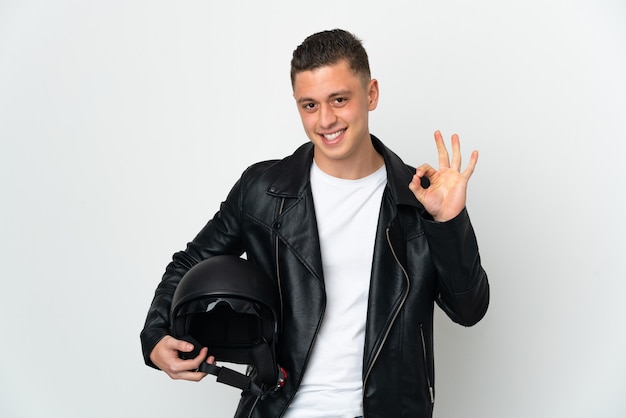 Caucasian man with a motorcycle helmet isolated on white wall showing ok sign with fingers