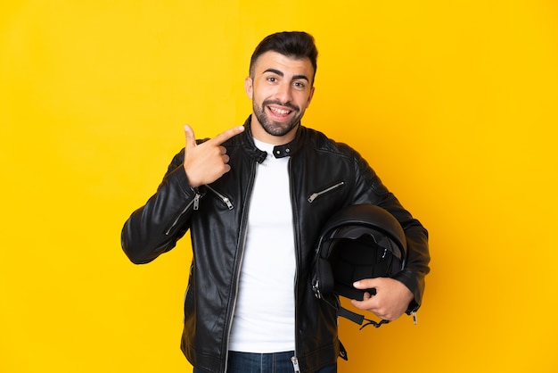 Caucasian man with a motorcycle helmet over yellow giving a thumbs up gesture