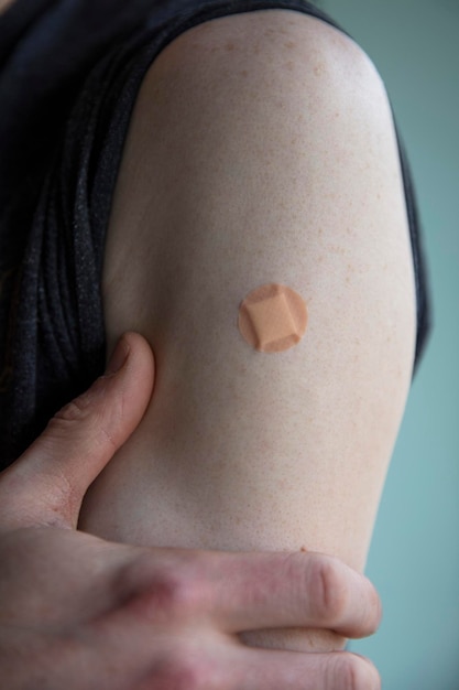 Foto uomo caucasico con un cerotto sul braccio dopo un'iniezione di vaccinazione