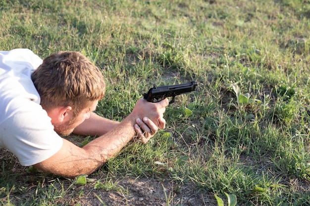 공압 권총을 손에 든 백인 남자는 무기에 대한 열정을 목표로 하고 복사 공간을 쏘고 있다