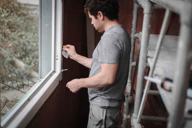 Caucasian man with a sponge washes the window frame