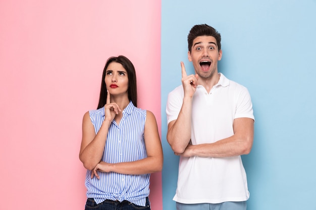 caucasian man and woman in casual wear touching chins and thinking, isolated over colorful wall