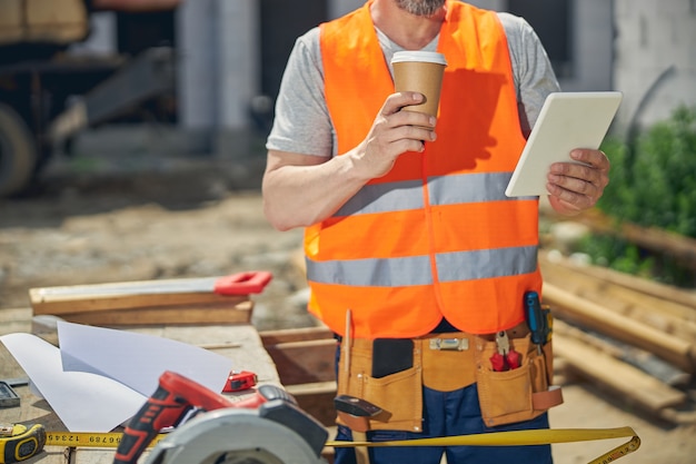 Caucasian man in workwear holding a tablet computer in his hand