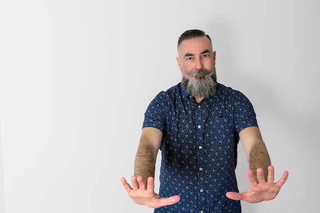 Foto uomo caucasico di anni con una grande barba mezza grigia con una faccia seria e le mani in avanti in un chiaro segno che gli ordina di fermarsi