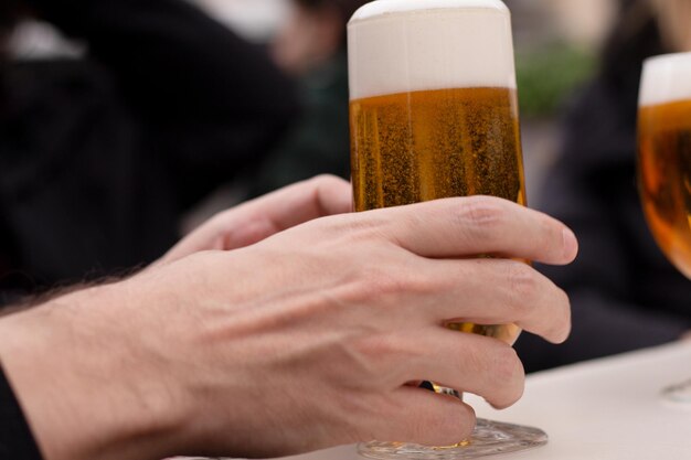 Caucasian man39s hand holding a beer in glass outdoors