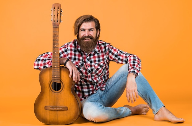 Caucasian mature hipster guitar palyer with trendy hairstyle in checkered shirt love music musical instrument