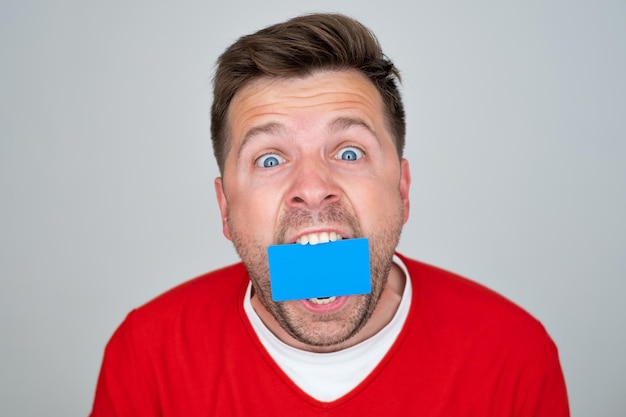 Caucasian mature man holding credit card at his mouth