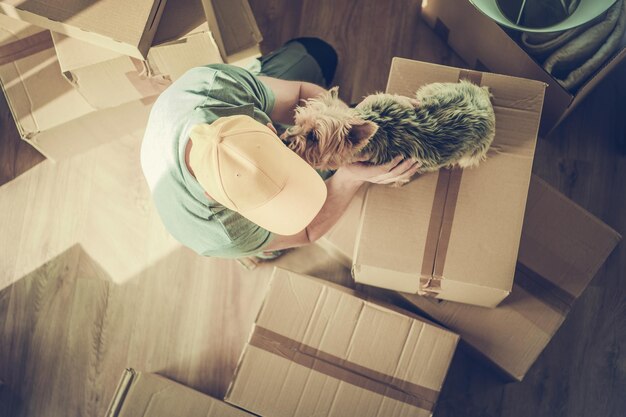 Photo caucasian men playing with his pet australian silky terrier while moving to new apartment dog licks his owner