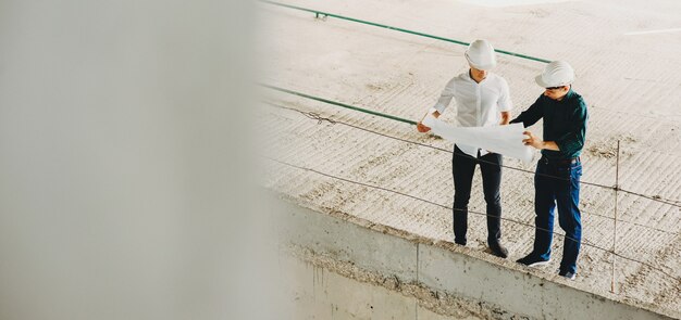 Photo caucasian men working with a new project posing with helmet on the newly constructed area