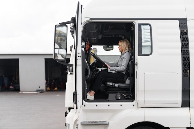 Foto donna caucasica di mezza età che guida camion camionista lavoratrice nel settore dei trasporti