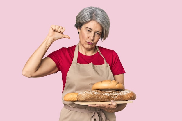 Caucasian midage baker with bread loaves feels proud and self confident example to follow