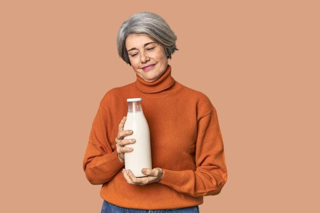 Photo caucasian midage female holding milk bottle happy smiling and cheerful