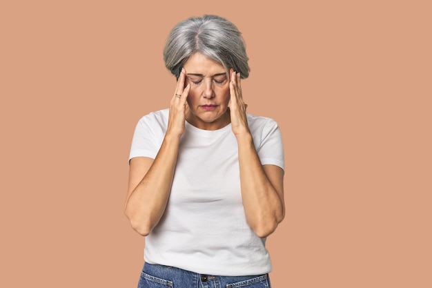 Photo caucasian midage female on studio background touching temples and having headache