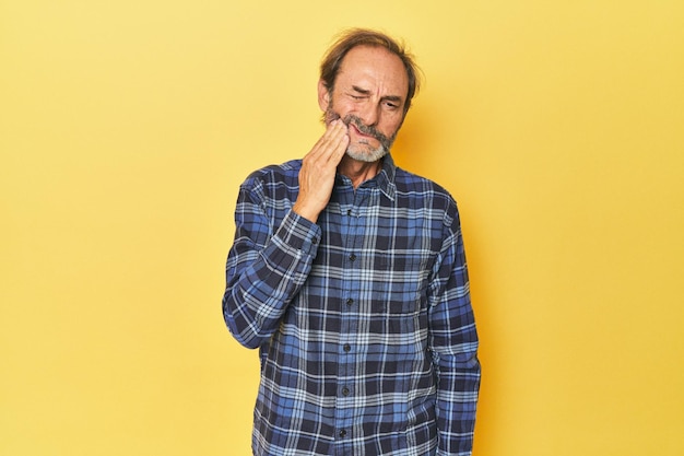 Caucasian middleaged man in yellow studio having a strong teeth pain molar ache