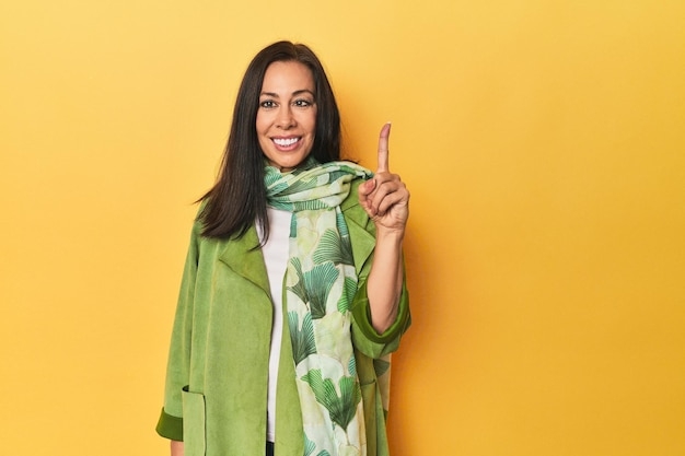 Photo caucasian middleaged woman against yellow backdrop showing number one with finger