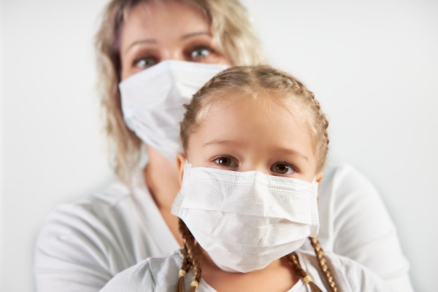 Caucasian mom and her daughter in white medical masks