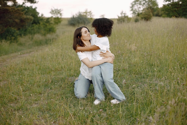 写真 白人の母親と彼女のアフリカ系アメリカ人の娘が屋外で一緒に抱きしめる