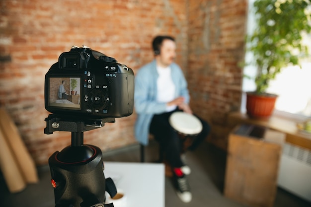 Caucasian musician playing hand drum during online concert at home isolated and quarantined. 