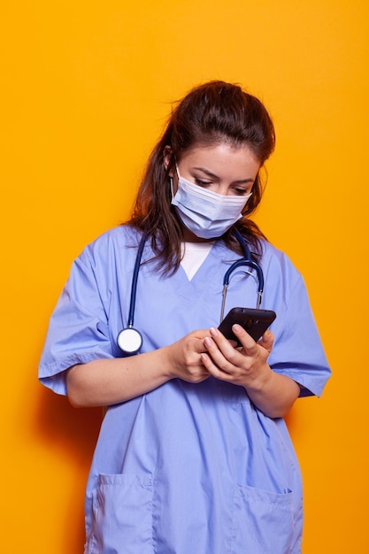 Caucasian nurse looking at smartphone with technology