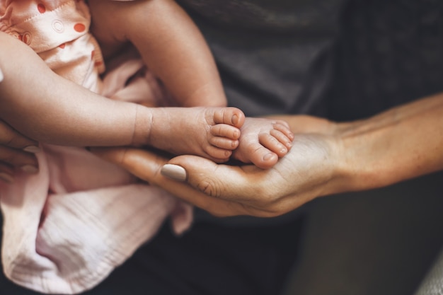 写真 彼女が眠っている間、彼の生まれたばかりの娘の足を手に持っている白人の親