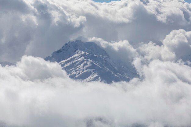Caucasian peak is covered with snow in the window of the\
clouds