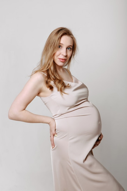 Фото Кавказская беременная женщина поглаживает живот на белом фоне копией пространства концепция здорового ди ...
