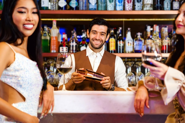 Кавказский профессиональный бармен или миксолог, готовящий коктейли для женщин в баре, привлекательный бармен