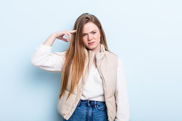 Caucasian red hair woman feeling confused and puzzled, showing you are insane, crazy or out of your mind