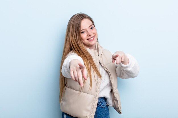 Caucasian red hair woman feeling happy and confident, pointing to camera with both hands and laughing, choosing you