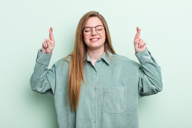 Caucasian red hair woman feeling nervous and hopeful, crossing fingers, praying and hoping for good luck