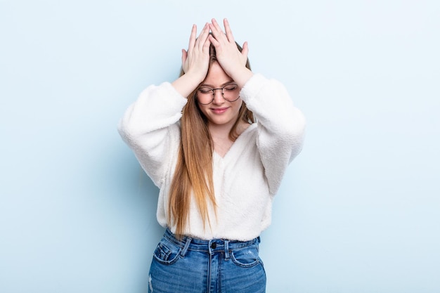 Foto donna caucasica dai capelli rossi che si sente stressata e ansiosa, depressa e frustrata da un mal di testa, alzando entrambe le mani alla testa