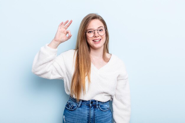 caucasian red hair woman feeling successful and satisfied, smiling with mouth wide open, making okay sign with hand