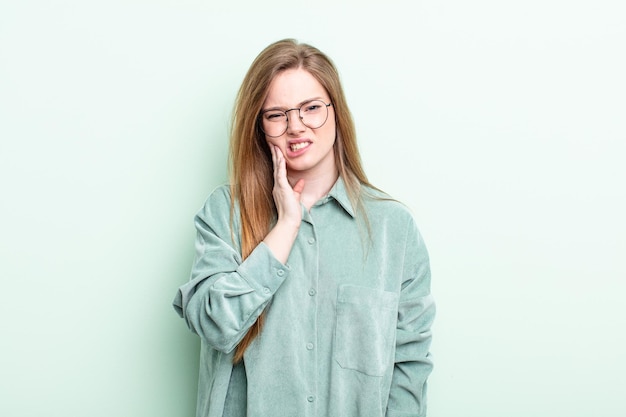 Caucasian red hair woman holding cheek and suffering painful toothache feeling ill miserable and unhappy looking for a dentist