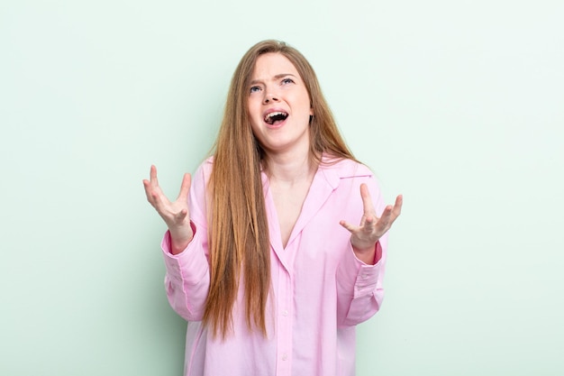 Caucasian red hair woman looking desperate and frustrated, stressed, unhappy and annoyed, shouting and screaming