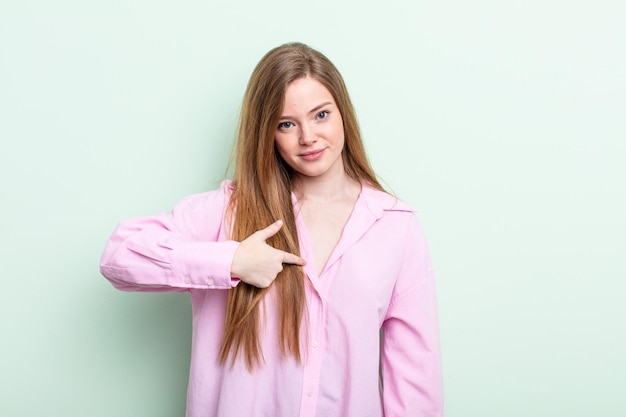 Caucasian red hair woman looking proud confident and happy smiling and pointing to self or making number one sign