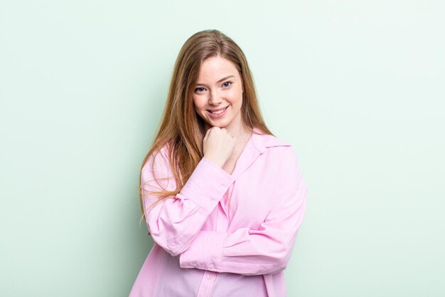 Caucasian red hair woman smiling enjoying life feeling happy friendly satisfied and carefree with hand on chin