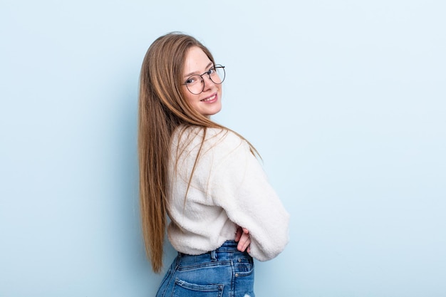 Caucasian red hair woman smiling gleefully, feeling happy, satisfied and relaxed, with crossed arms and looking to the side