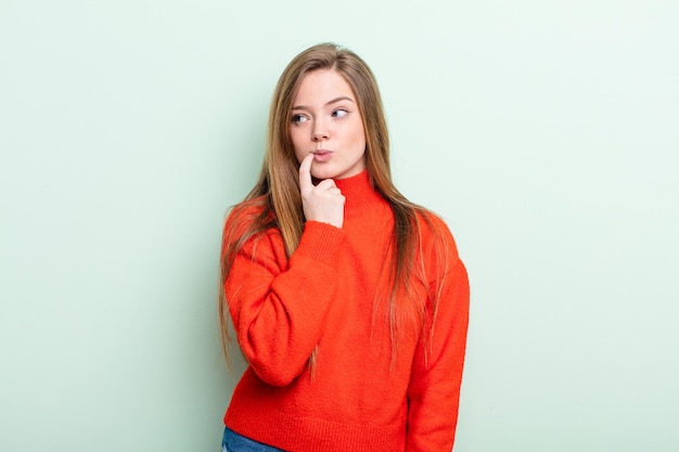 Caucasian red hair woman with surprised nervous worried or frightened look looking to the side towards copy space