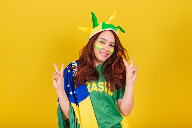 Caucasian redhaired woman soccer fan from brazil in peace and love pose