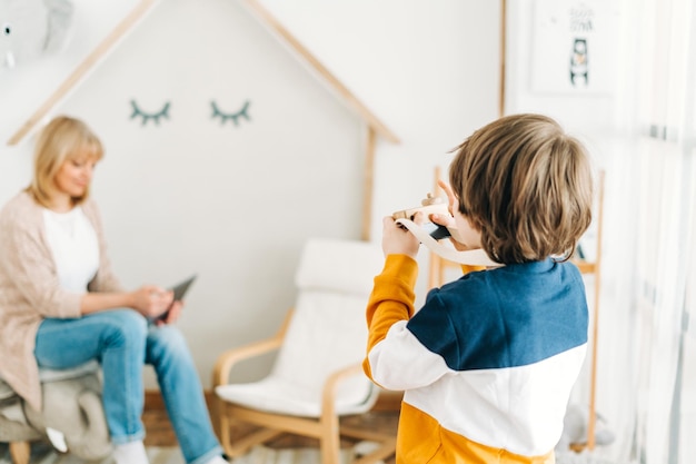 Caucasian school boy kid child taking a photo of his mother mom while she surfing the internet with