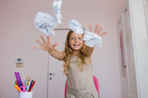 Caucasian schoolgirl having fun at recess or on vacation playing with mint crumpled paper made from school notebooks throws them Study fatigue