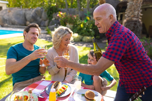 Caucasian senior man serving drinks for the family in garden